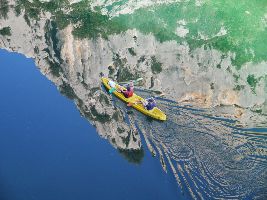 Personne qui fait diu kayak sur une rivière de rhône alpes avec le paysage qui se reflète dans l'eau