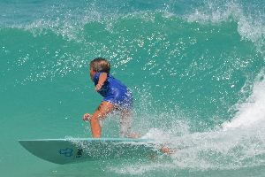Enfant qui surf sur une vague bleue turquoise